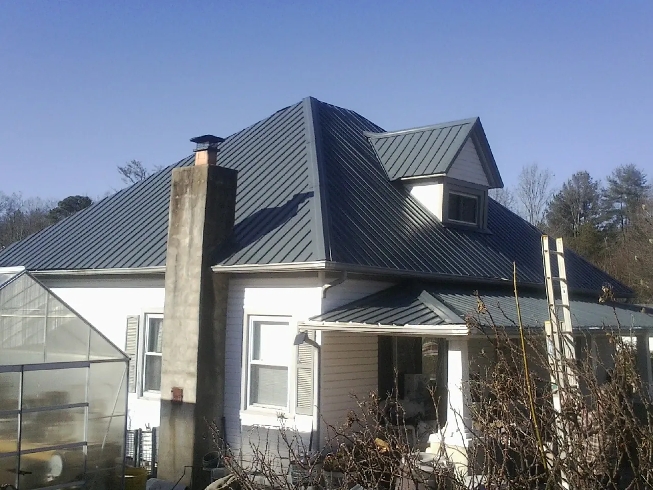 Dark blue standing seam metal roof on a white farmhouse with dormer — Slate & Tile Roof Repair by Roofing Brothers in Richmond Dale