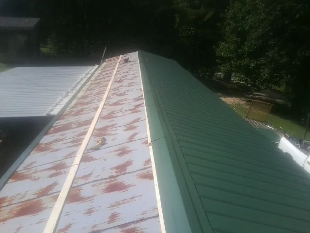 Old rusted panels beside newly installed green metal roofing — Wind Damage Roof Repair by Roofing Brothers in Richmond Dale