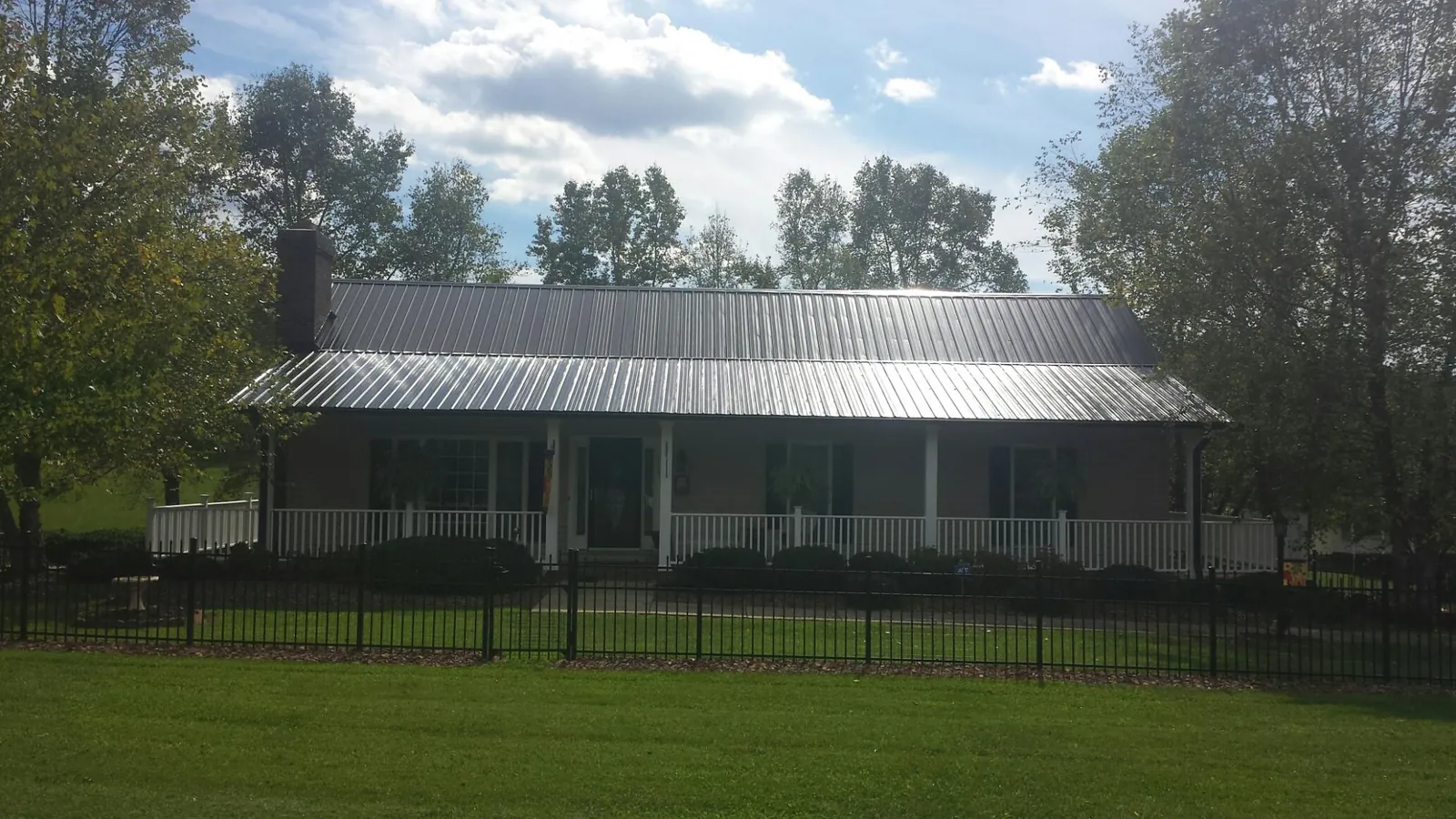 Gray metal roof on a brick ranch with a full width front porch — Gutter Guard Installation work by our crew in Richmond Dale