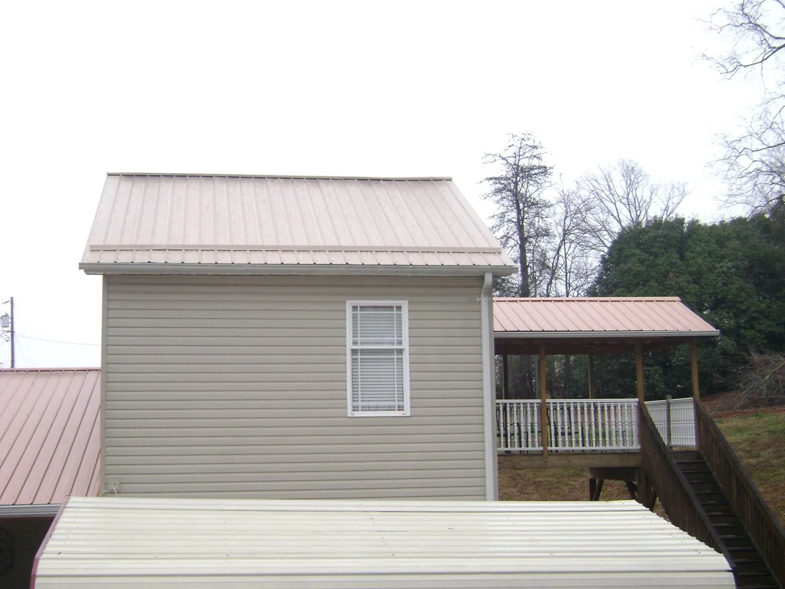 Tan metal roofs on a two story addition and attached porch, from a Roof Replacement job in Richmond Dale