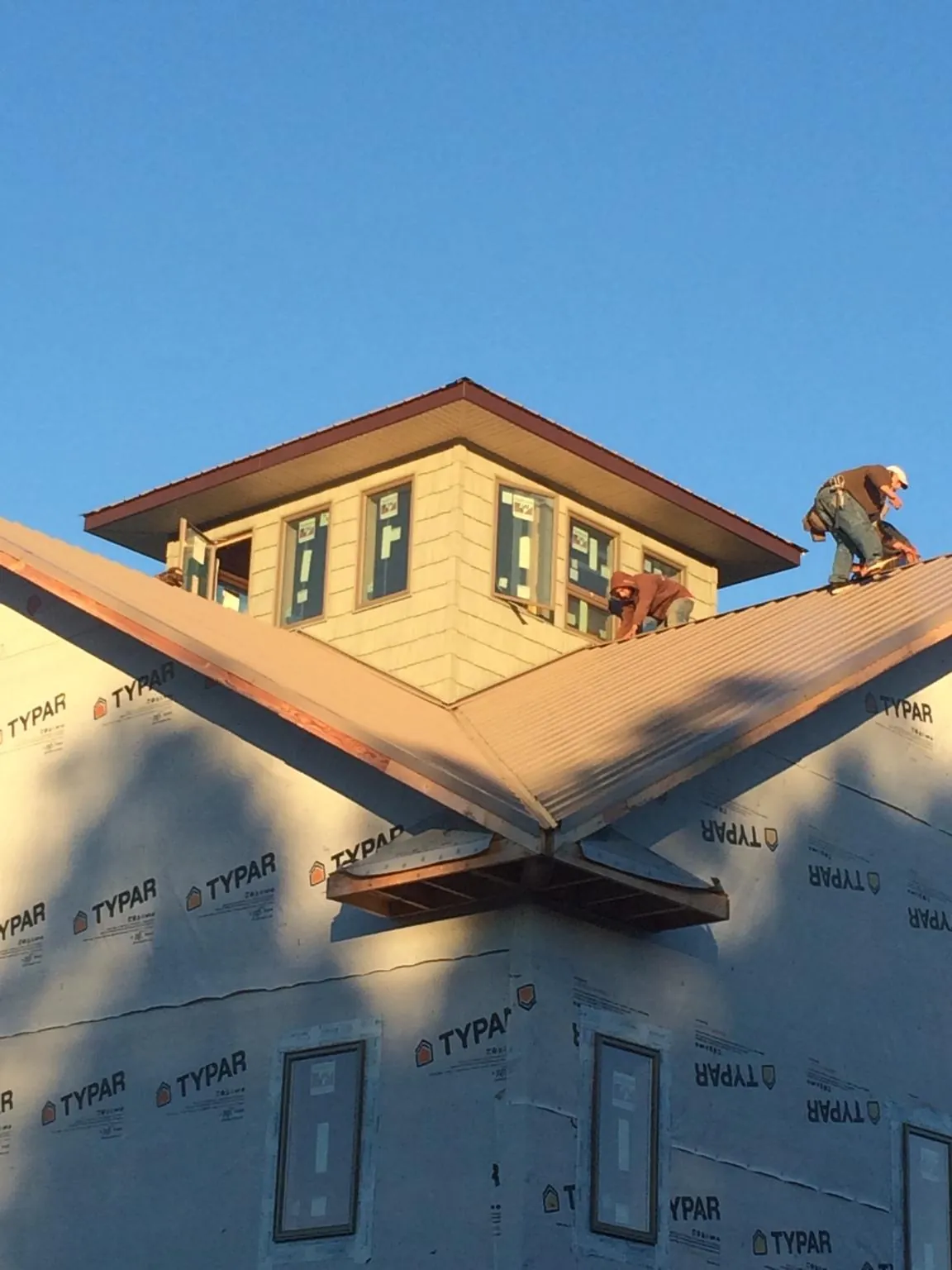 Roofers working around a rooftop cupola on a new metal roof at sunset — Roof Waterproofing in Richmond Dale by Roofing Brothers